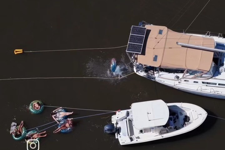 Two boats on the water with people swimming and relaxing on floats.