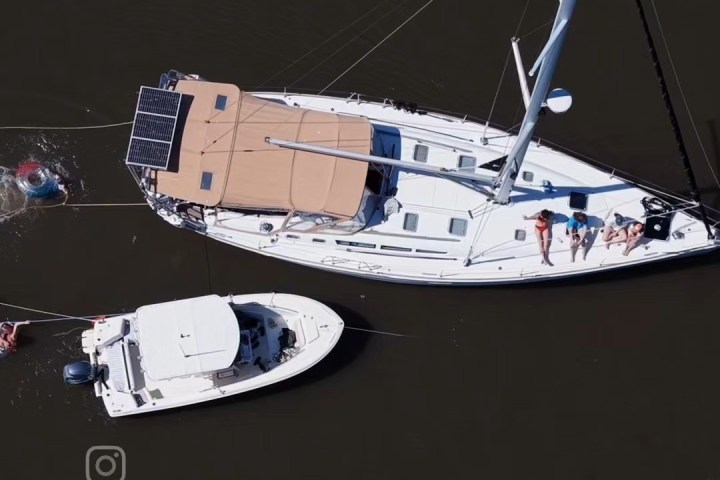 Aerial view of two boats on dark water with people swimming nearby.