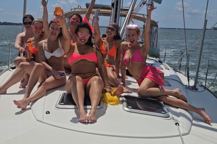 Group of people in swimsuits celebrating on a sailboat.