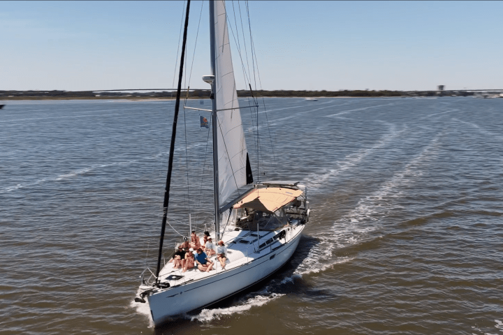 Sailboat with passengers sailing on open water under clear skies.