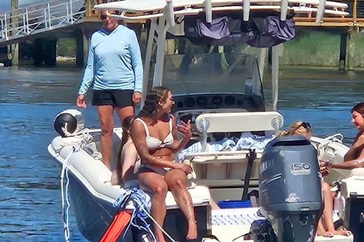 People relaxing on a boat in a sunny river setting.