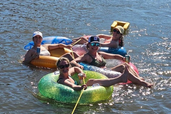 Four people relaxing on inflatables in a sunny river.