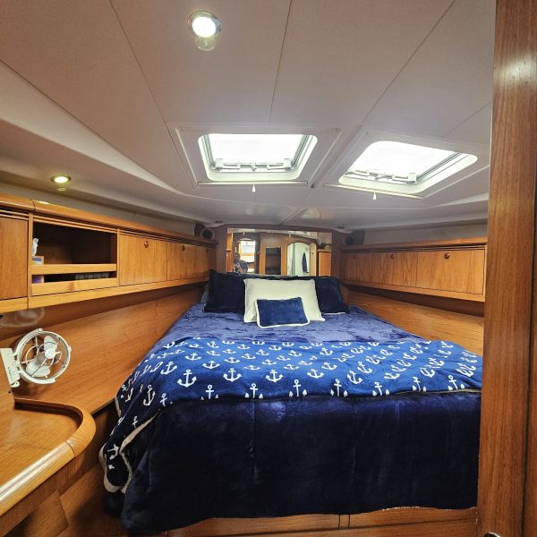 Cozy yacht cabin with a bed, blue anchor-patterned blanket, and wooden interior.