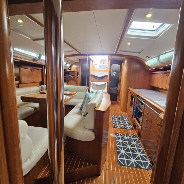 Interior of a yacht with wooden furnishing, white cushions, and skylights.
