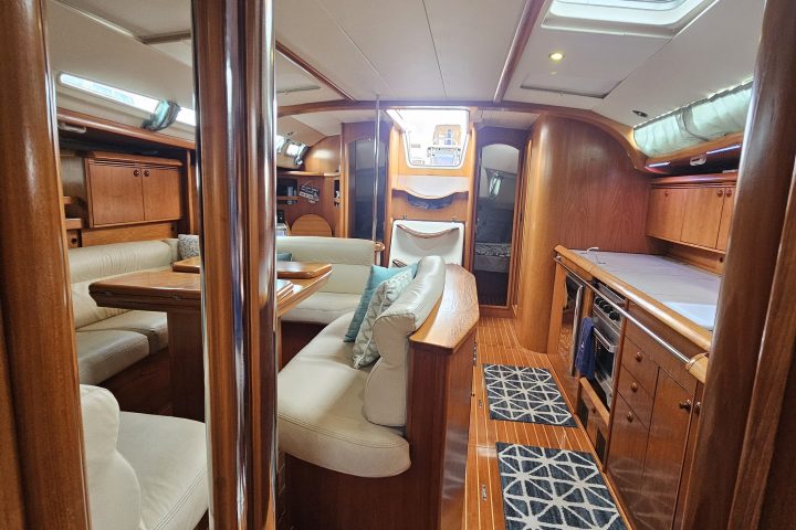 Interior of a yacht with wooden furnishing, white cushions, and skylights.