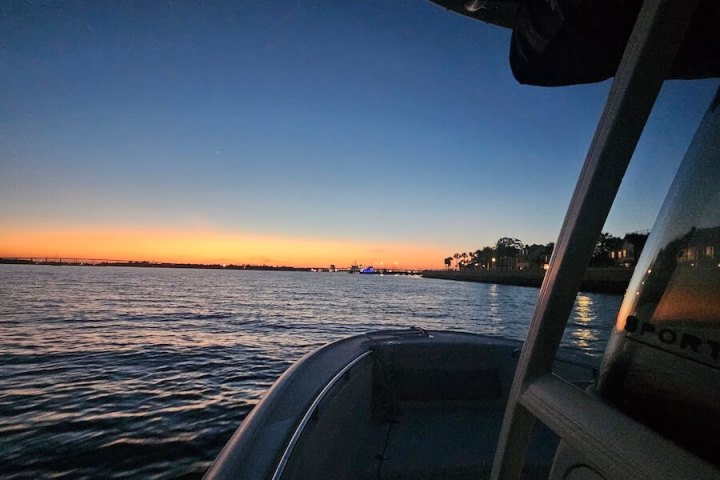 Boat on calm water at sunset with a view of the horizon.