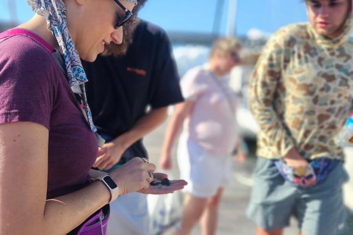 People standing on a dock, one person examining an object in hand.