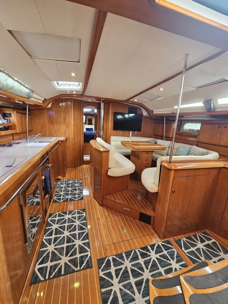 Boat interior with wooden decor, seating area, TV, and carpeted floor.