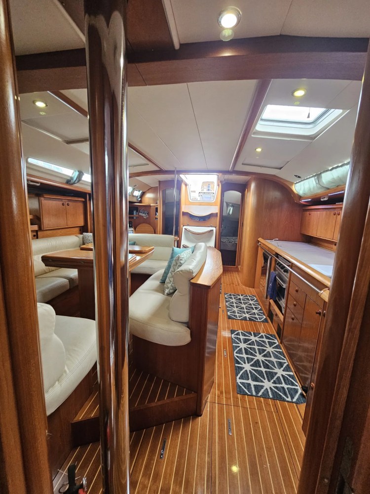 Interior of a yacht with wood paneling and white seating, skylights above.