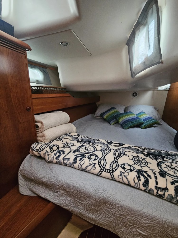 Cozy boat cabin with a bed, pillows, and rolled towels.