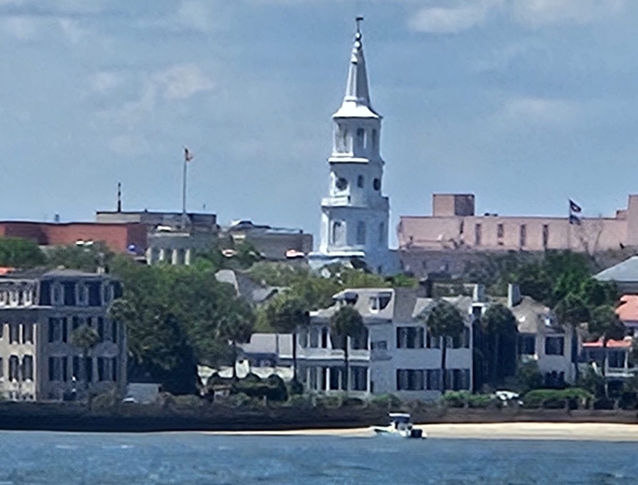 City skyline with a white church spire near a waterfront.