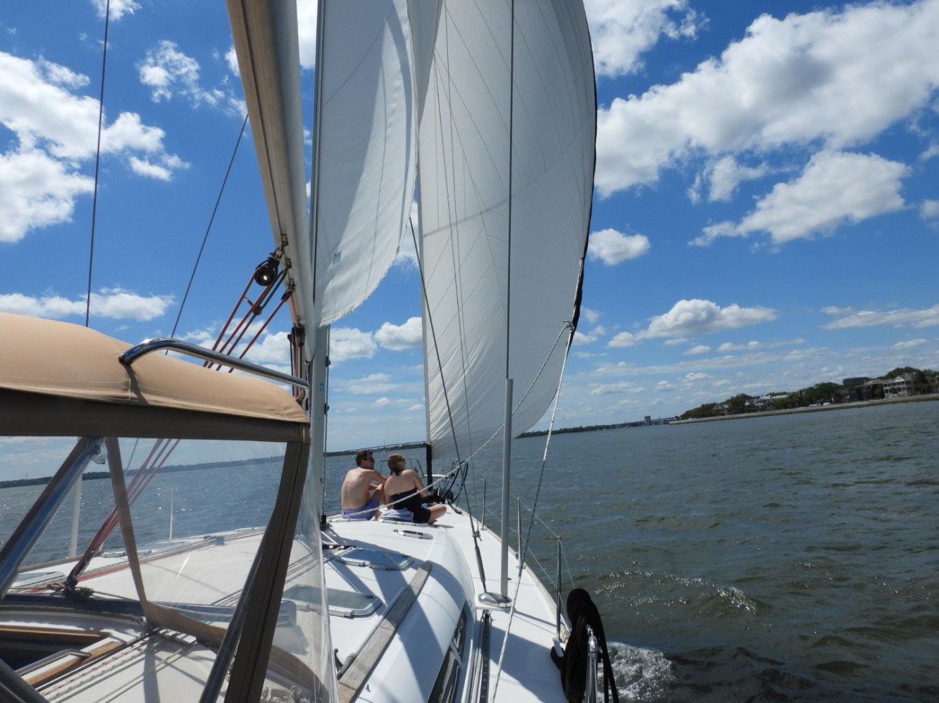 Sailing boat on water with people onboard under a cloudy sky.