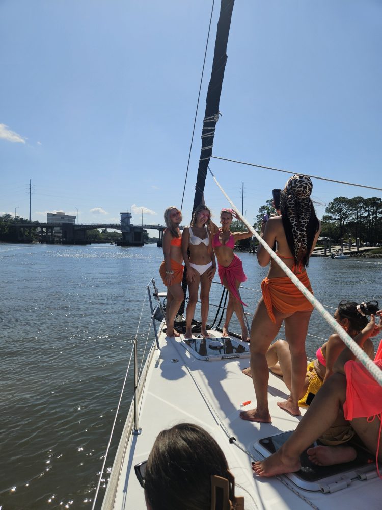 People in swimsuits enjoying a sunny day on a sailboat.
