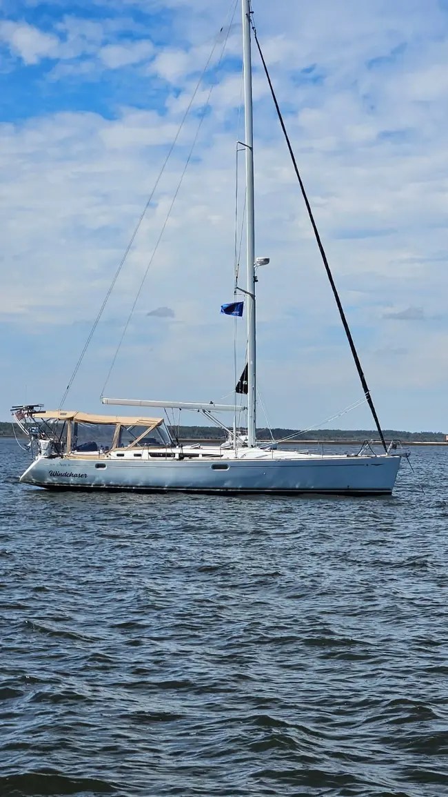 Sailboat on calm water under blue sky with clouds.