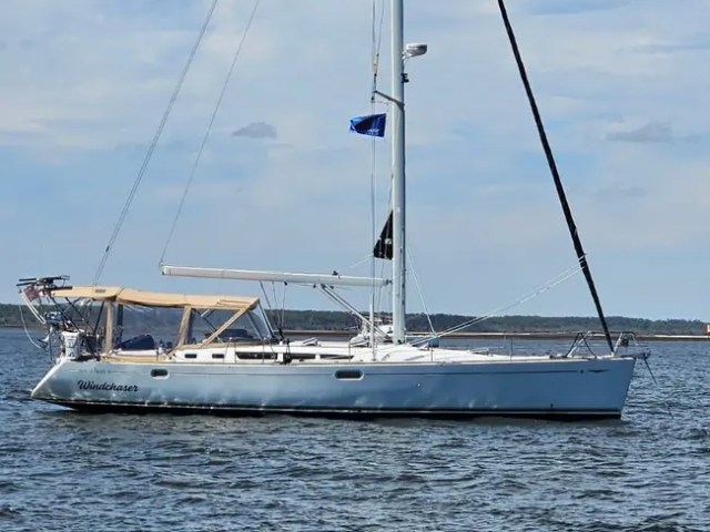 Sailboat on calm water under blue sky with clouds.